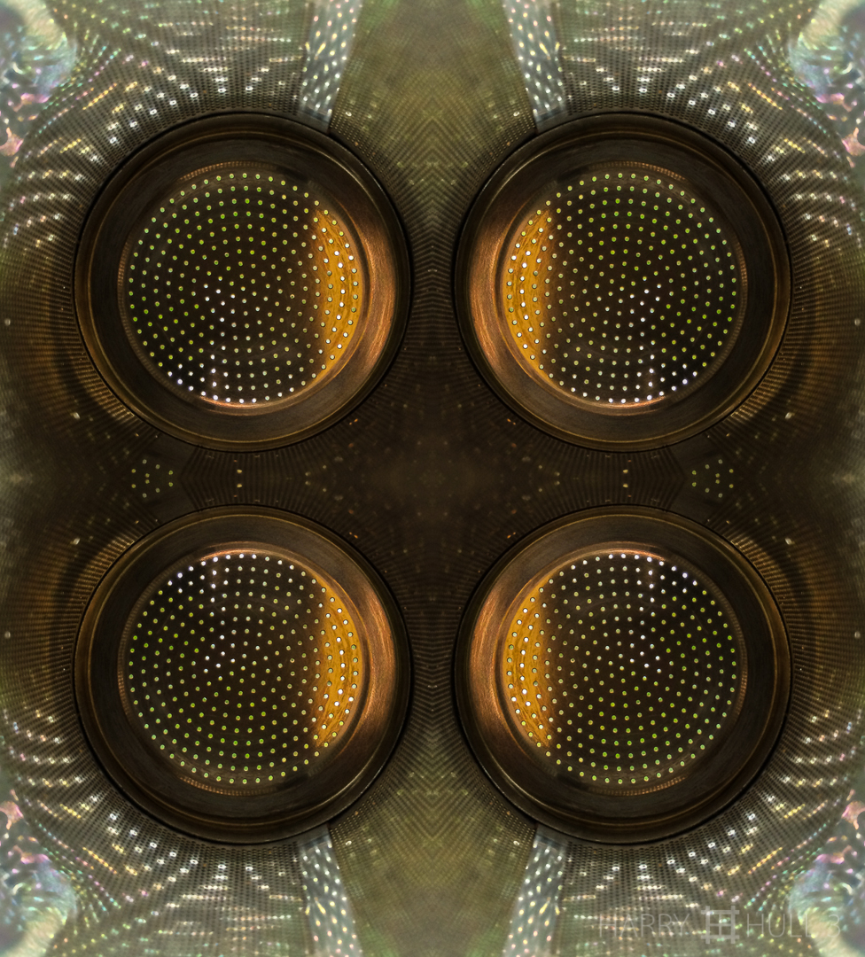 Perforated light. iPhone photo of the inside of a stainless steel tea strainer with sunlight beyond.