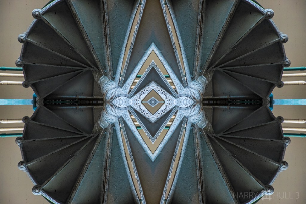 Under the stairs. Photo from below of a metal spiral staircase in Cell Block A, Alcatraz National Park, San Francisco, California.